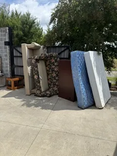 Before: mattresses, couch and furniture stacked by a fence